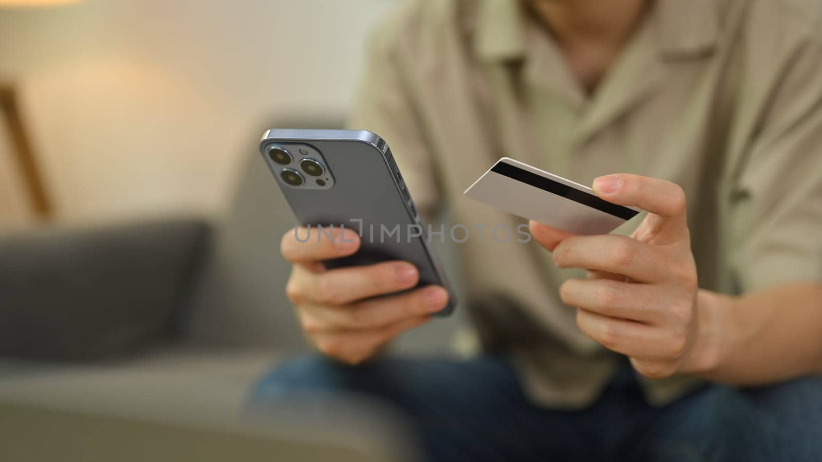 Cropped image of man hand holding credit card making transaction or using mobile bank application.