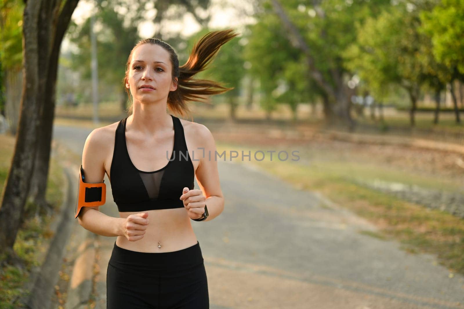 Image of attractive fitness woman jogging in the park with sunrise light. Fitness, sport and healthy lifestyle concept.