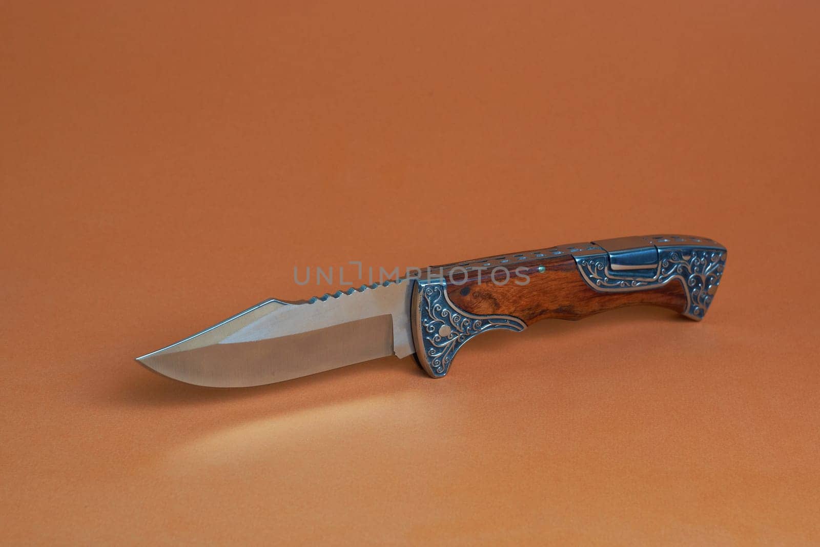 hunting knife on a brown background with a beautiful metal pattern on the handle