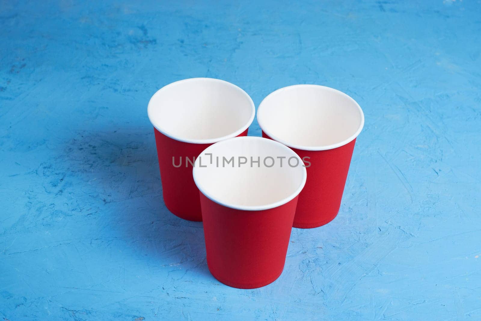 three red paper coffee cups on a blue background with a place to copy the text. Morning concept.