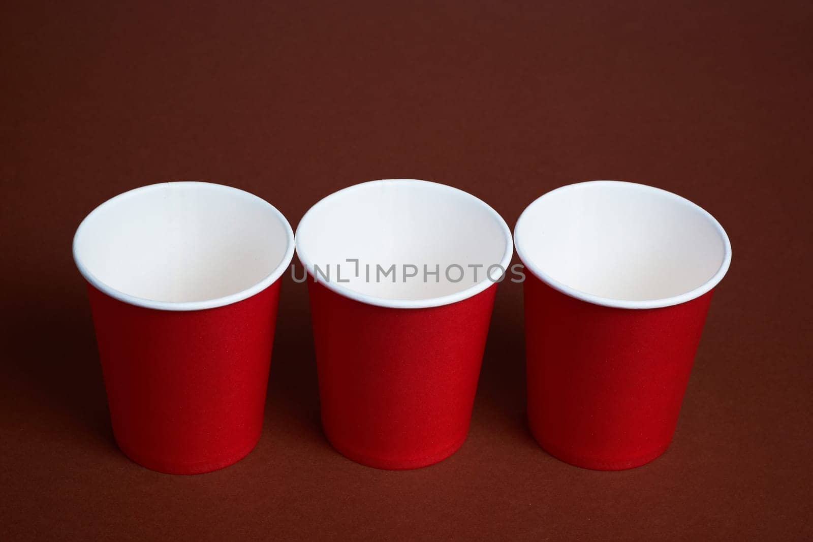 three red paper coffee cups on a dark brown background. Morning concept.