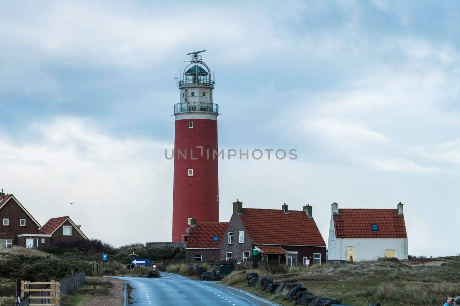 Red lighthouse at the little isle of Texel, the Netherlands with small small old red h and white houses by compuinfoto