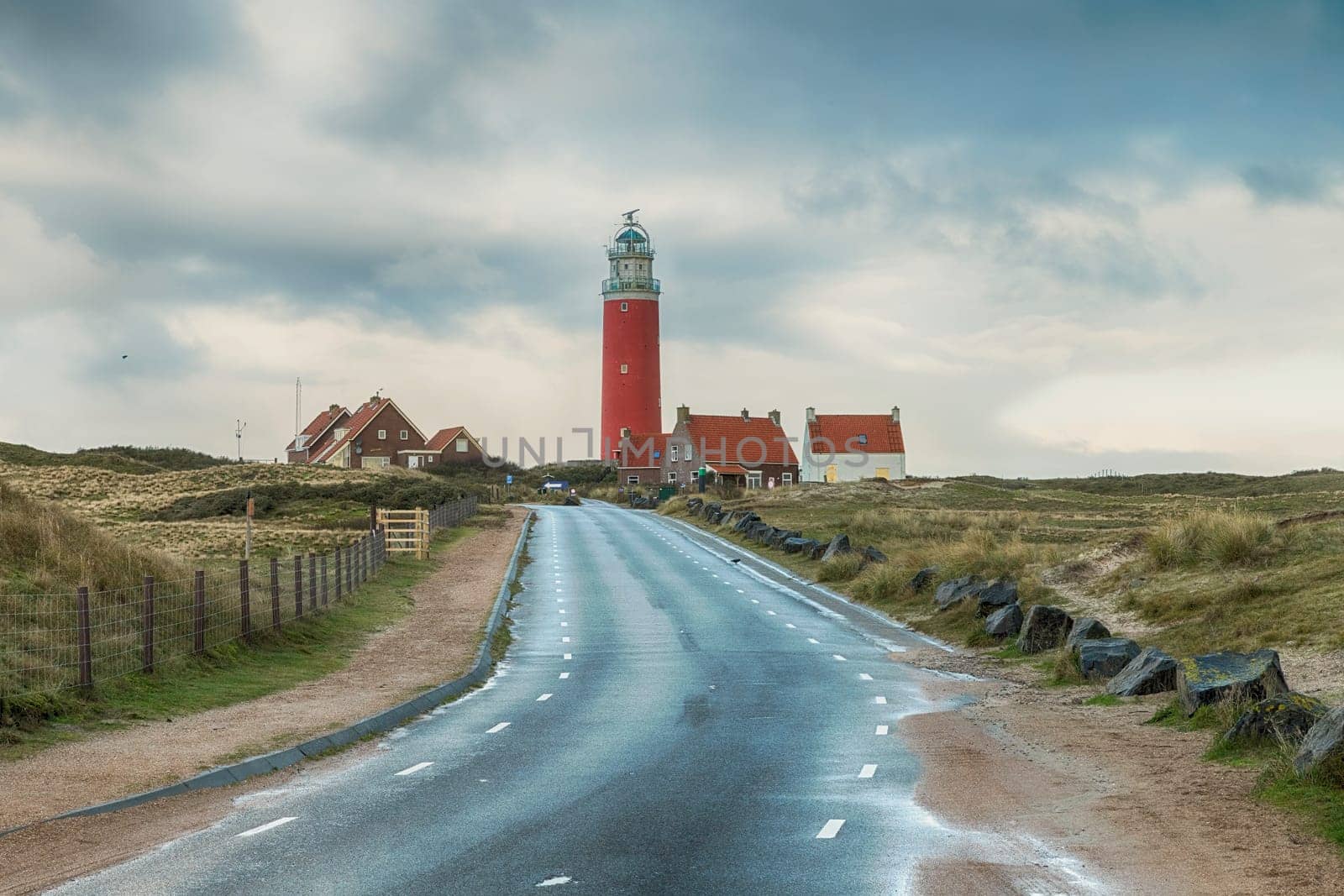 Red lighthouse at the little isle of Texel, the Netherlands with small small old red h and white houses by compuinfoto