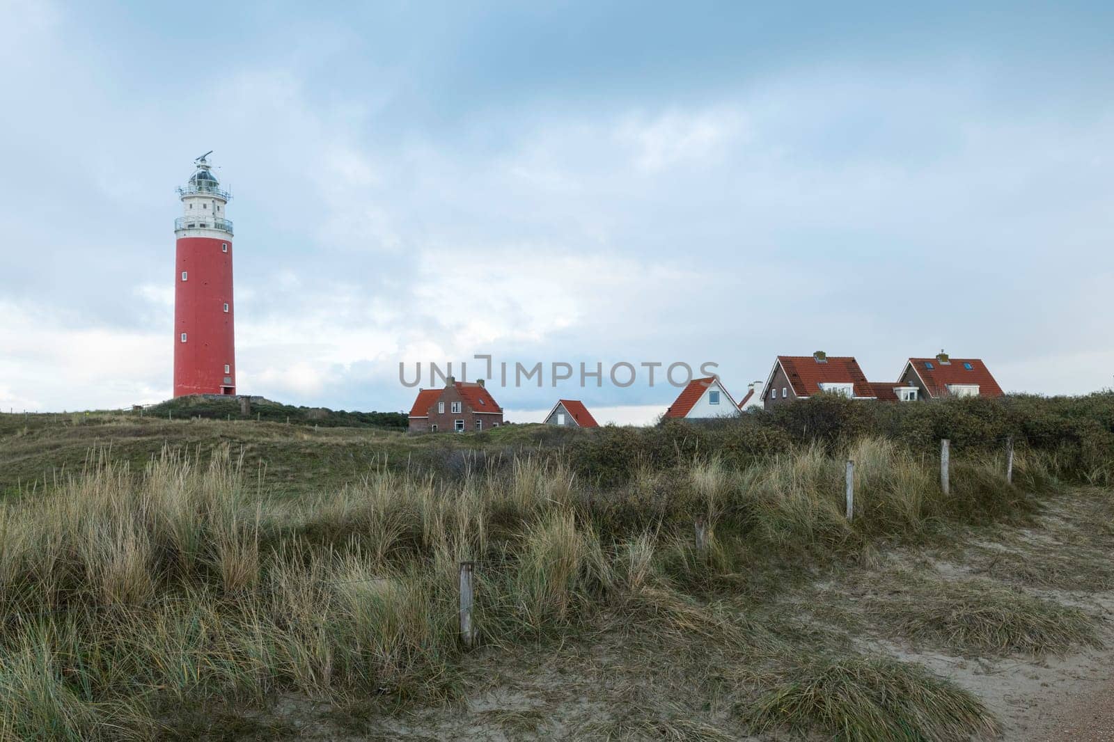 Red lighthouse at the little isle of Texel, the Netherlands with small small old red h and white houses