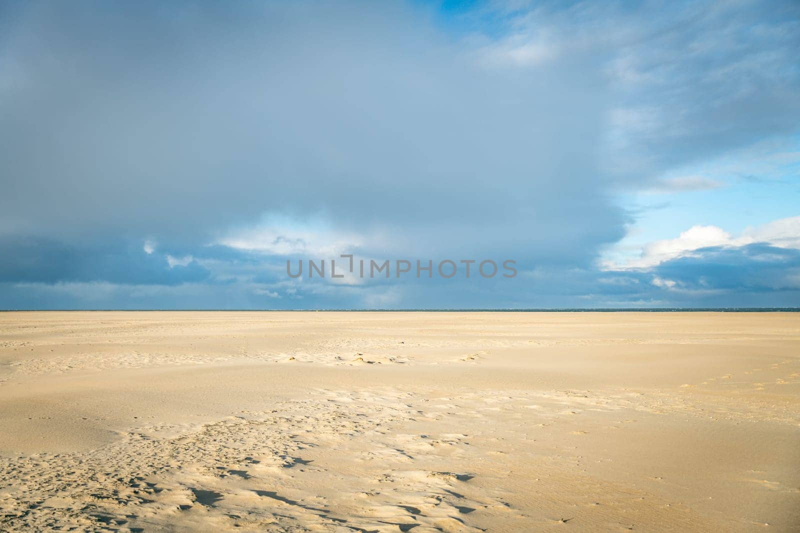 the large empty beach on the island of Texel with the horizon and dark clouds in the background