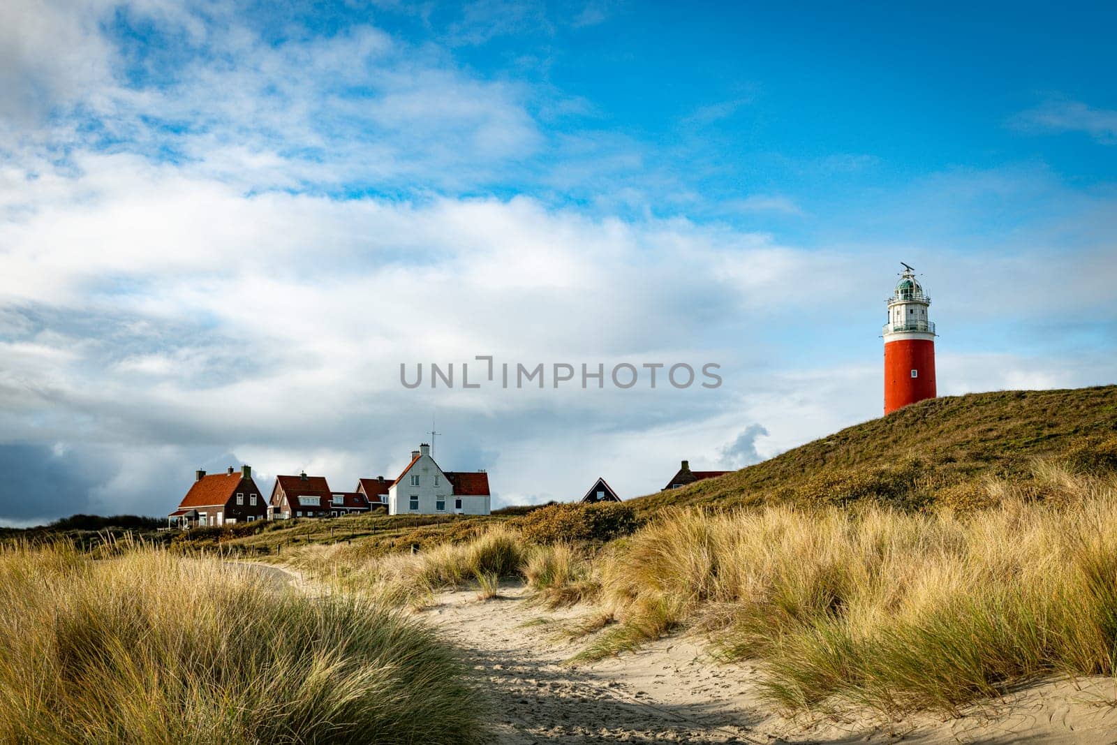 Red lighthouse at the little isle of Texel, the Netherlands with small old red and white white houses