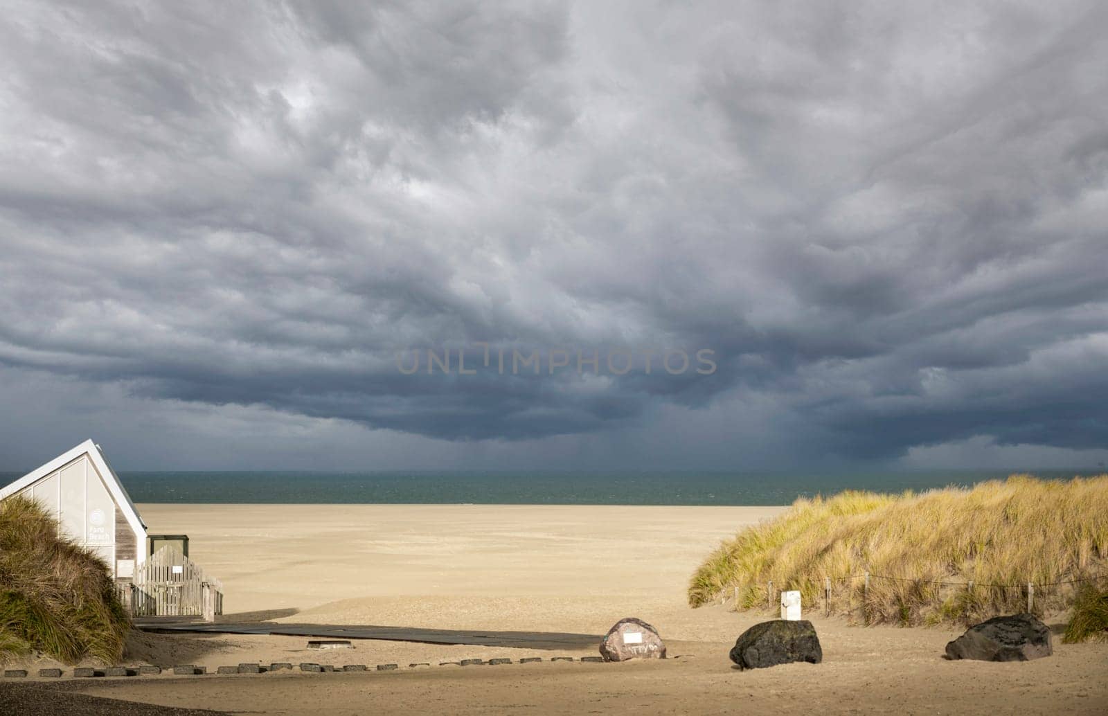 the entrance to an empty beach with the sea and the horizon in the background by compuinfoto