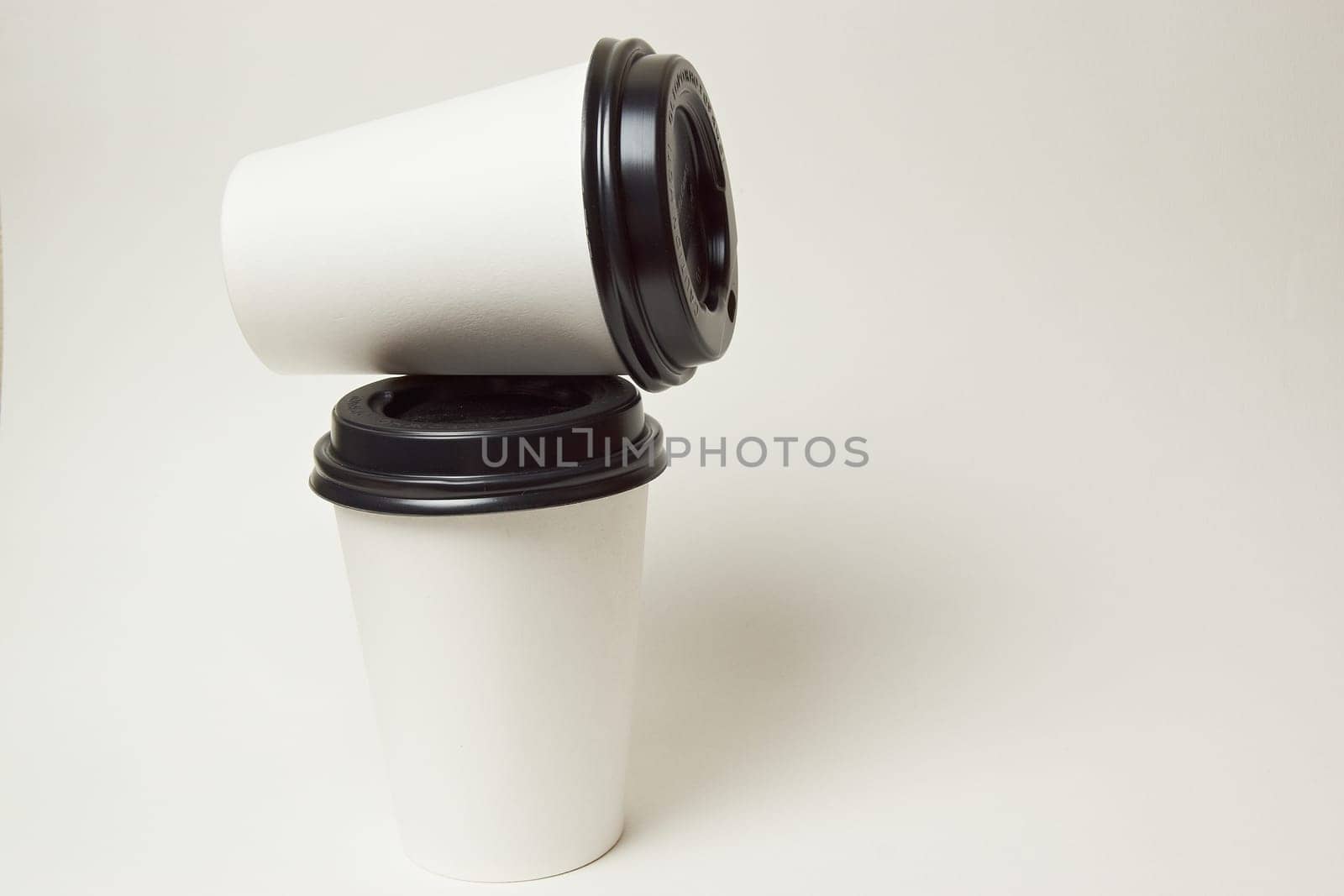 Paper coffee container with black lid and coffee beans on a white background white coffee paper cup with black lid takeaway coffee