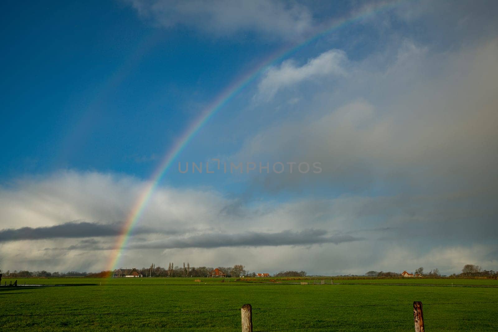 blue sky with rainbow over the fields by compuinfoto