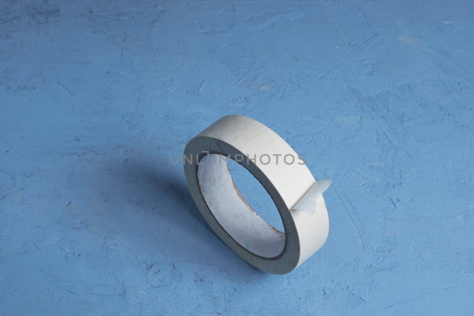 Extreme close-up image of a roll of adhesive tape on a blue background