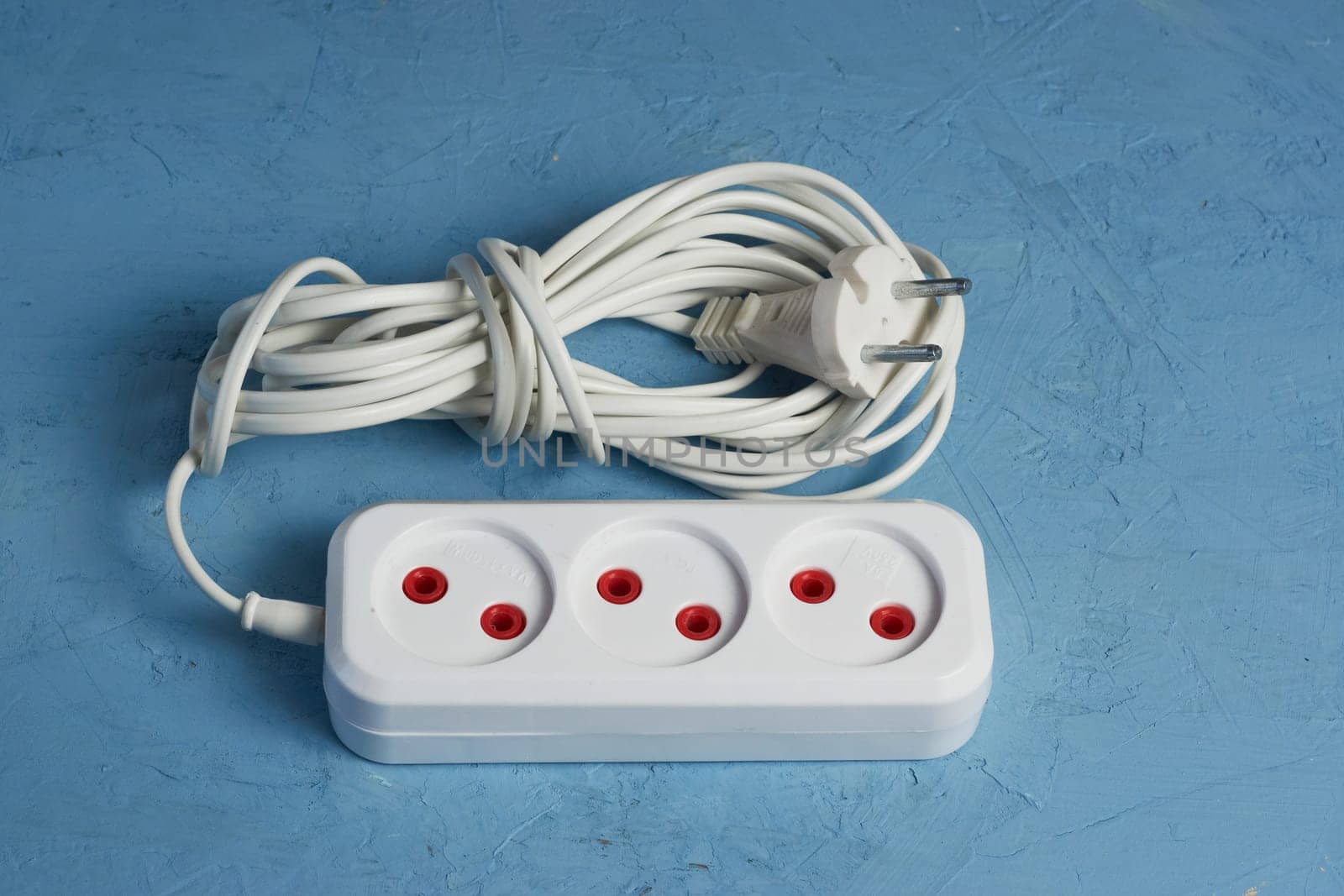 Power strip with three connectors and on a blue background. Energy consumption concept