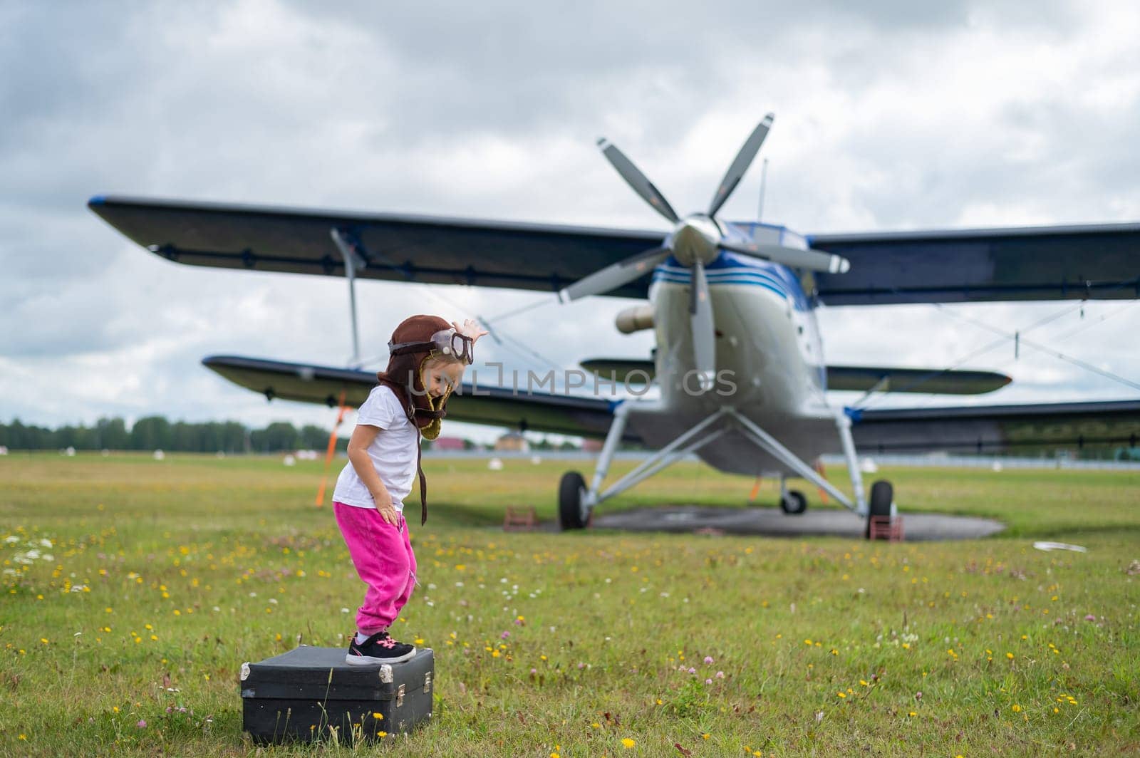 A cute little girl playing on the field by a four-seater private jet dreaming of becoming a pilot by mrwed54