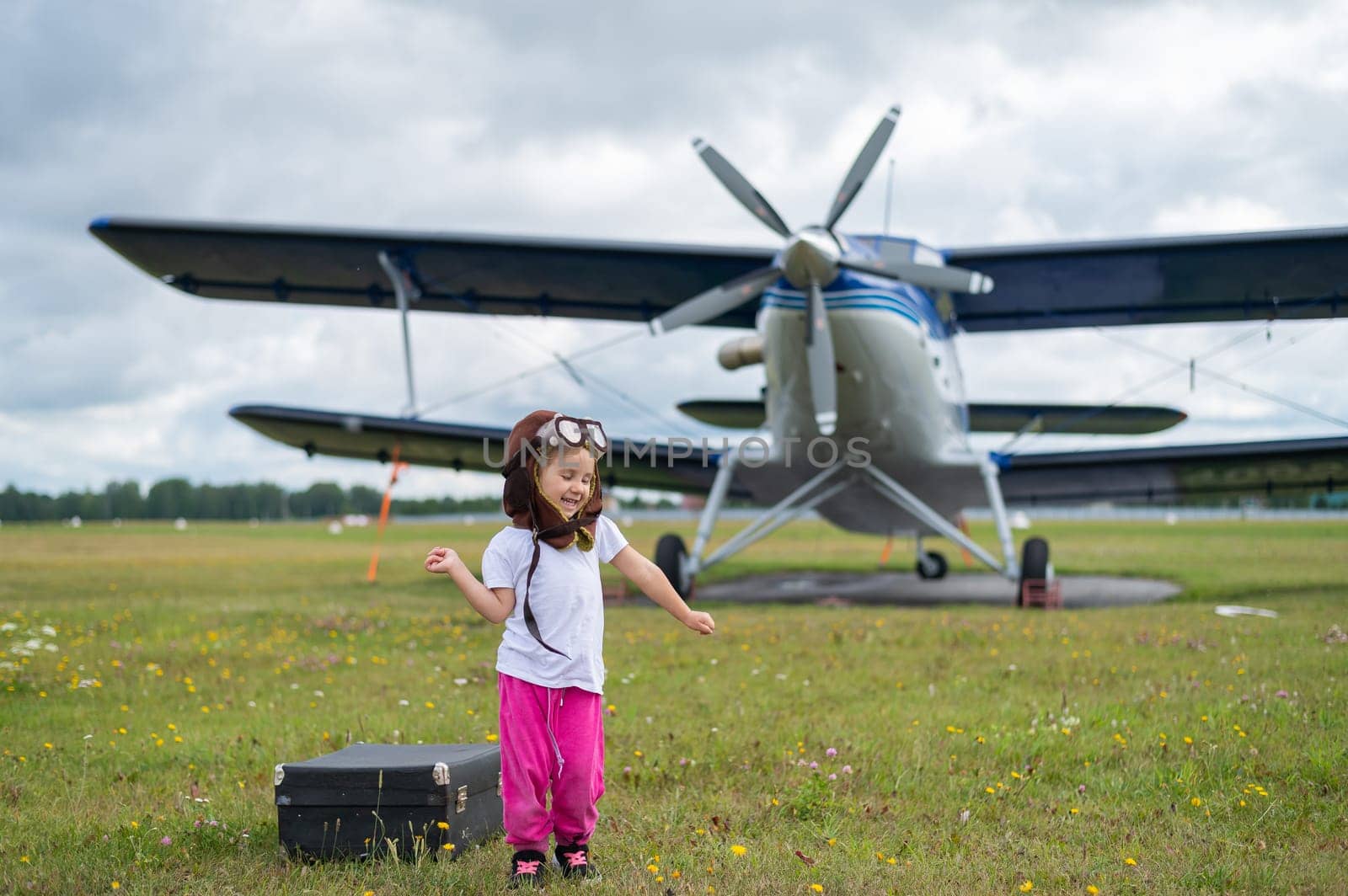 A cute little girl playing on the field by a four-seater private jet dreaming of becoming a pilot.