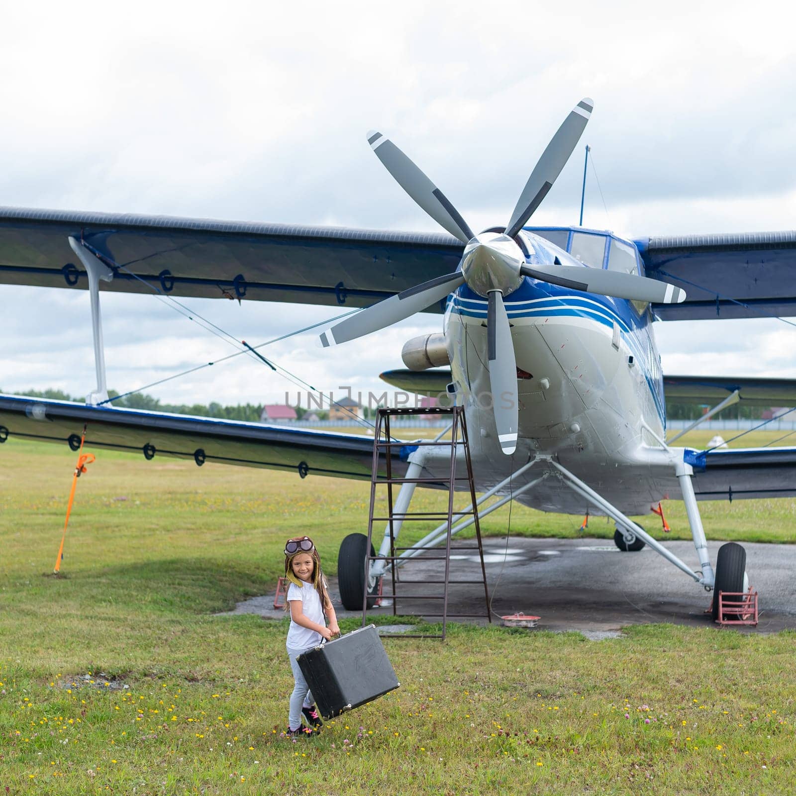 A cute little girl playing on the field by private jet dreaming of becoming a pilot by mrwed54