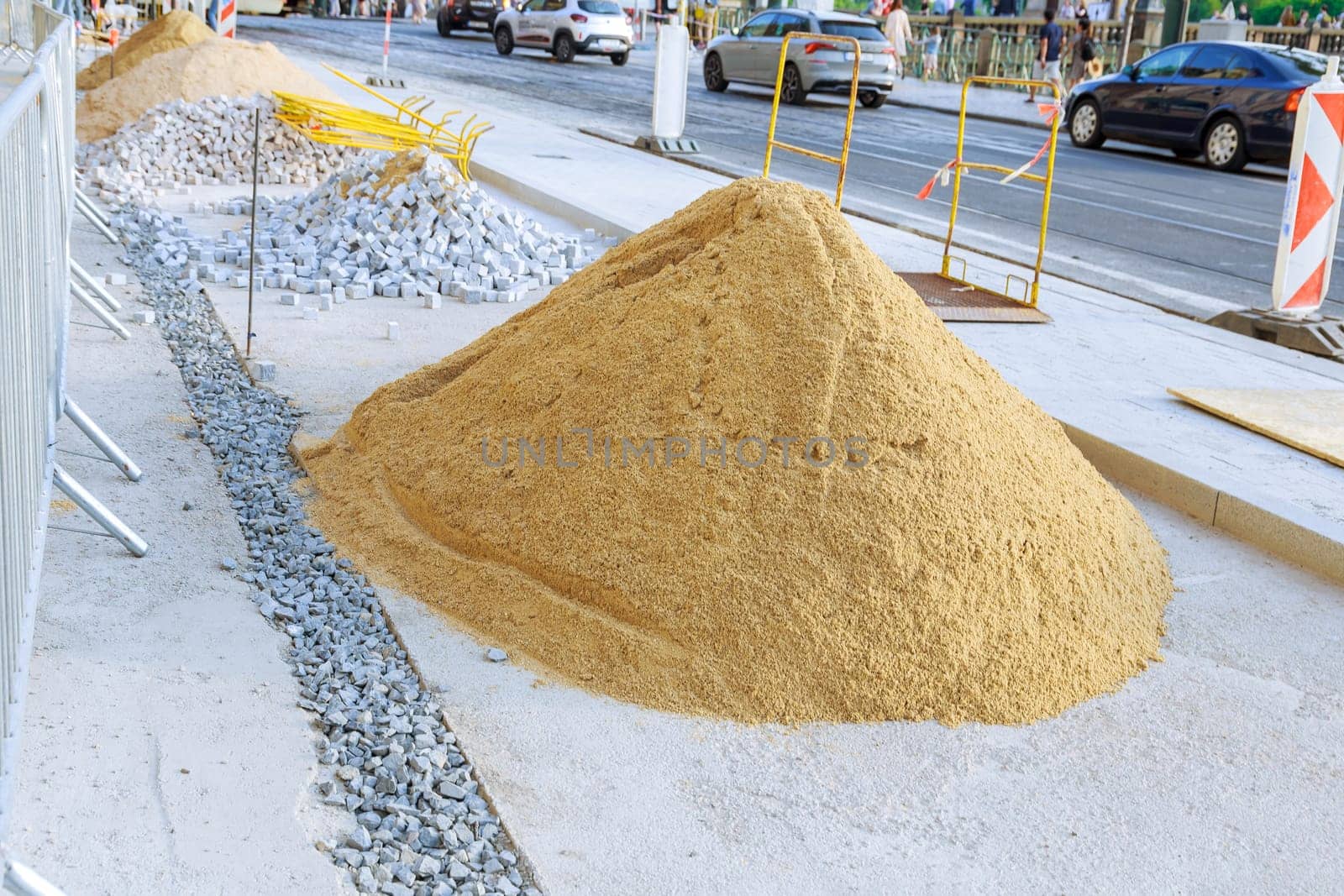 A pile of sand lying on a new pavement for paving and jointing. Laying paving stones of white and gray color, small size in the city. Arrangement of city infrastructure.