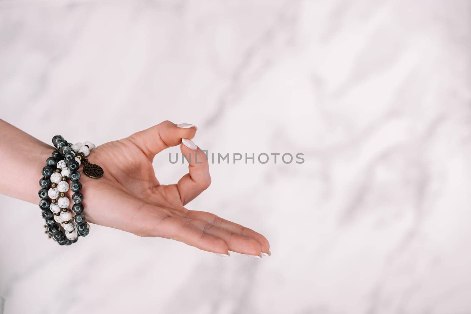 Jnana Gian mudra - Om on white background. Female hand with mala beads bracelet. Woman meditating, doing yoga