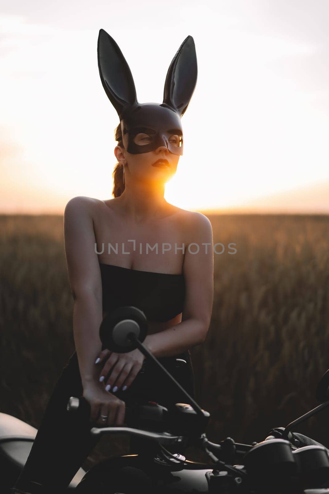 Sexy motorcyclist woman sits on motorcycle. Attractive driver in rabbit mask on face. Trip, speed, style, feminism concept.