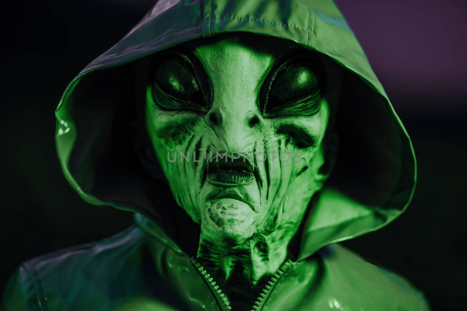 Spooky alien in field under green neon light. Scary mask, vinyl smooth raincoat. UFO, extraterrestrial life, halloween cosplay concept. High quality photo