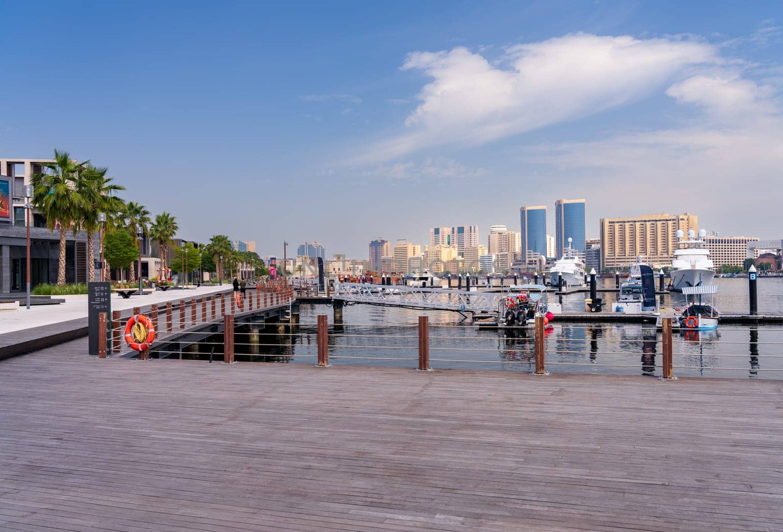 View along the Creek towards Deira with large boats docked by the Al Seef boardwalk in Dubai, UAE