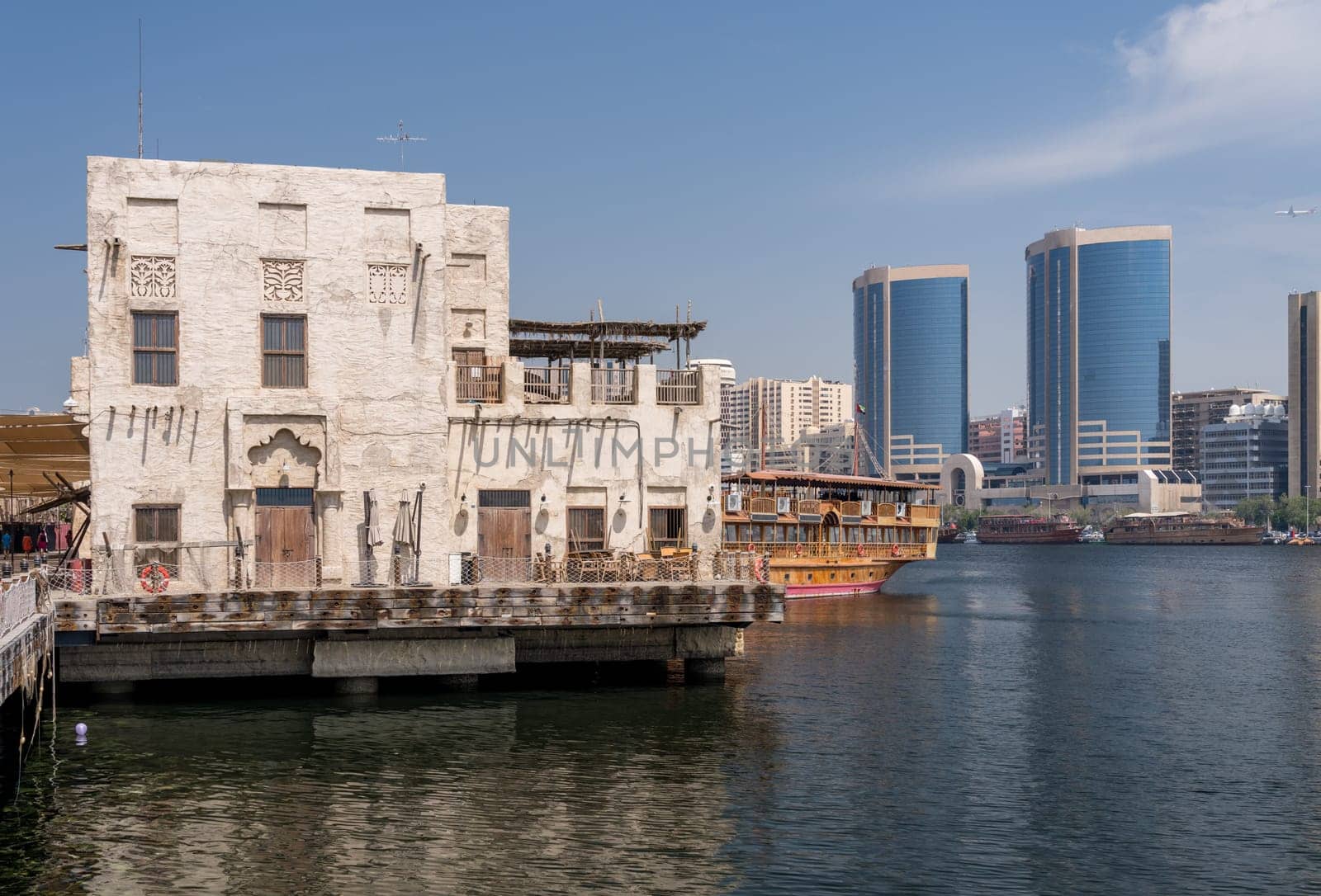 View along the Creek towards Deira with large dhow tour boats docked by the Al Seef boardwalk in Dubai, UAE