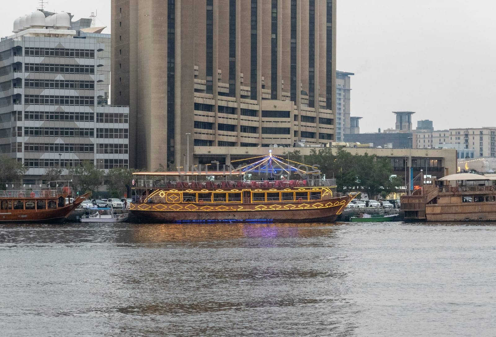 View along the Creek towards Deira with large dhow tour boats docked by the Al Seef boardwalk in Dubai, UAE