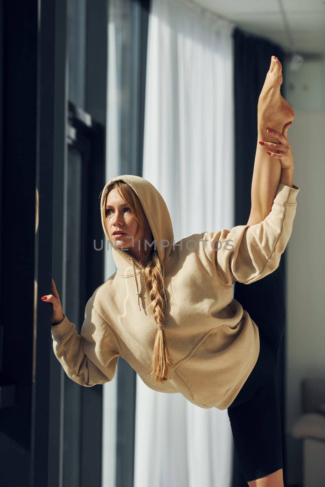 Posing for the camera. Woman in sportive clothes doing yoga indoors.