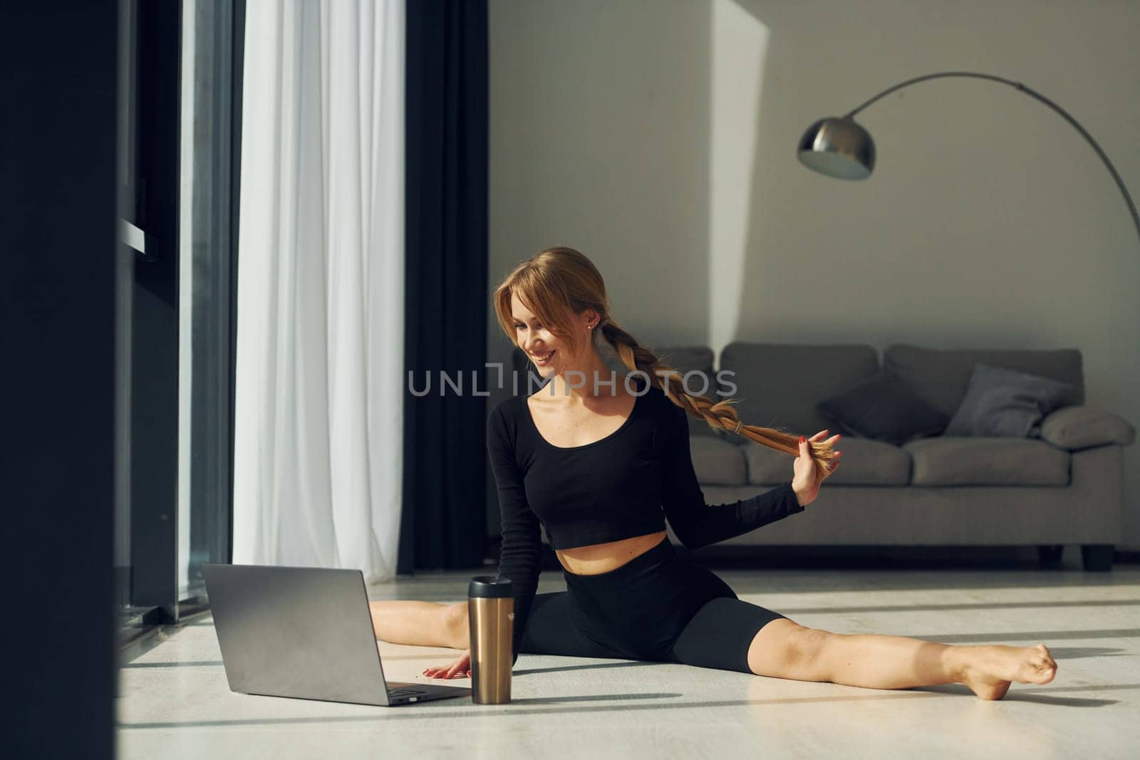 Using laptop. Woman in sportive clothes doing yoga indoors.