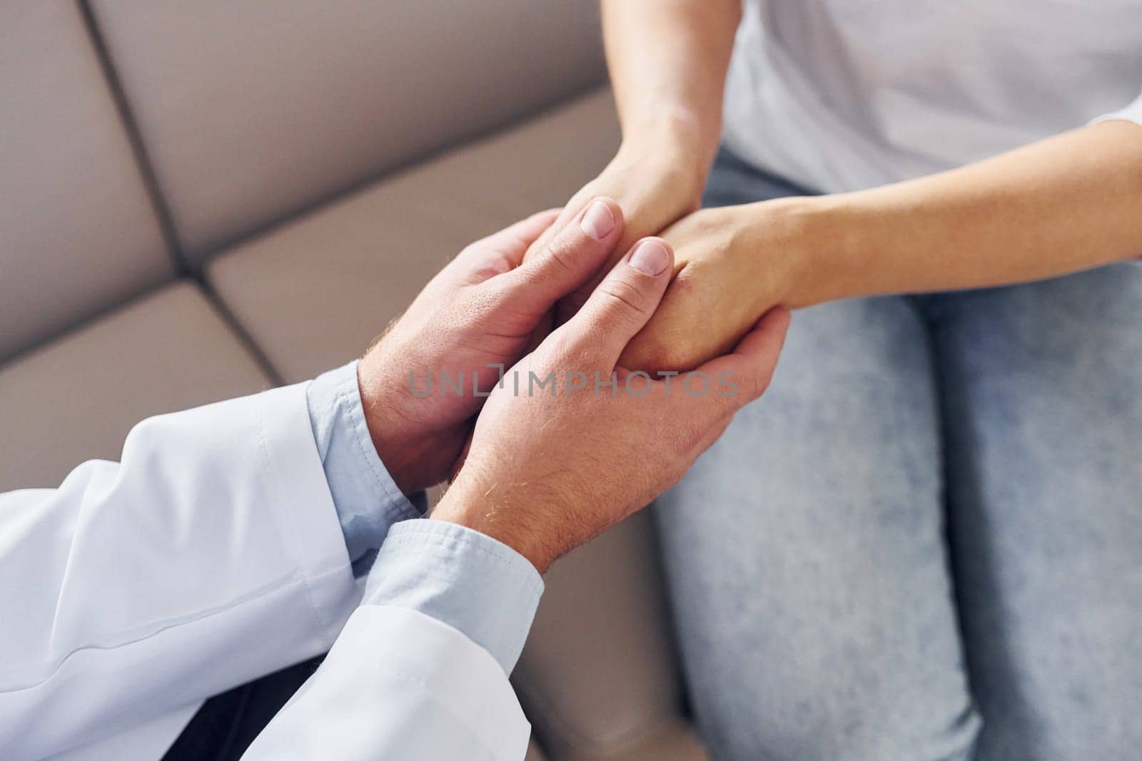 Holding customer by the hands. Professional medic in white coat is in the clinic.