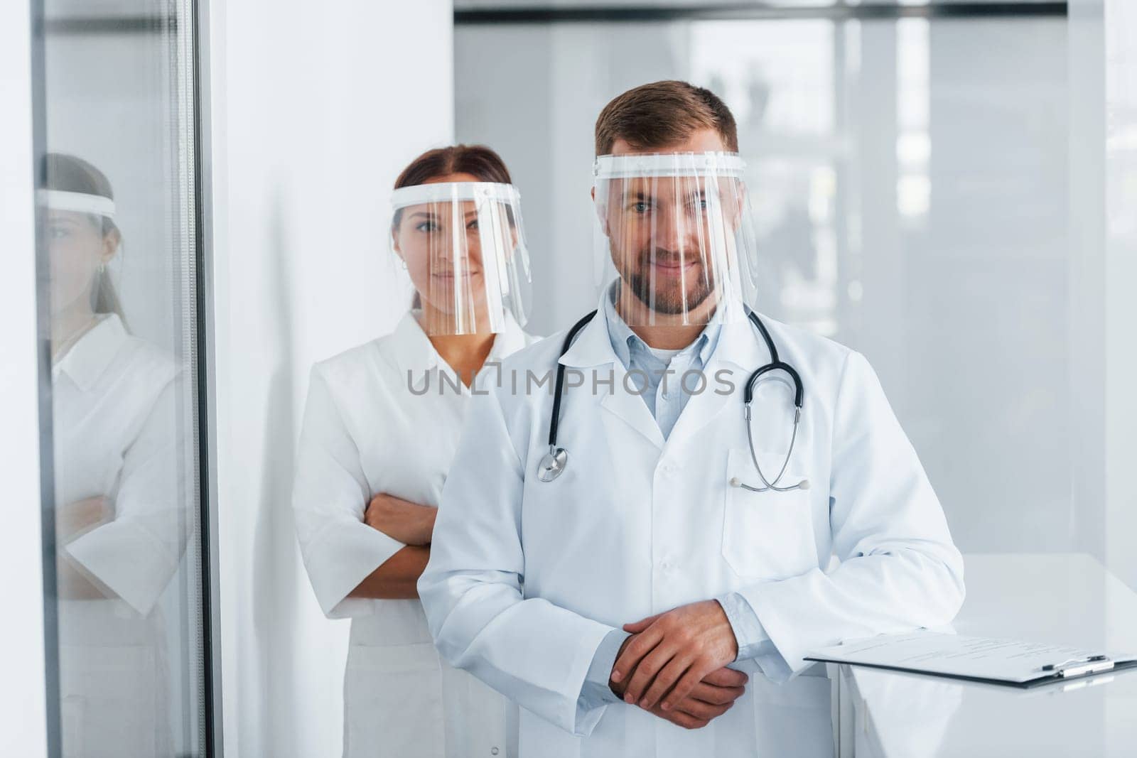 Front view. Two doctors in white coats is in the clinic working together.