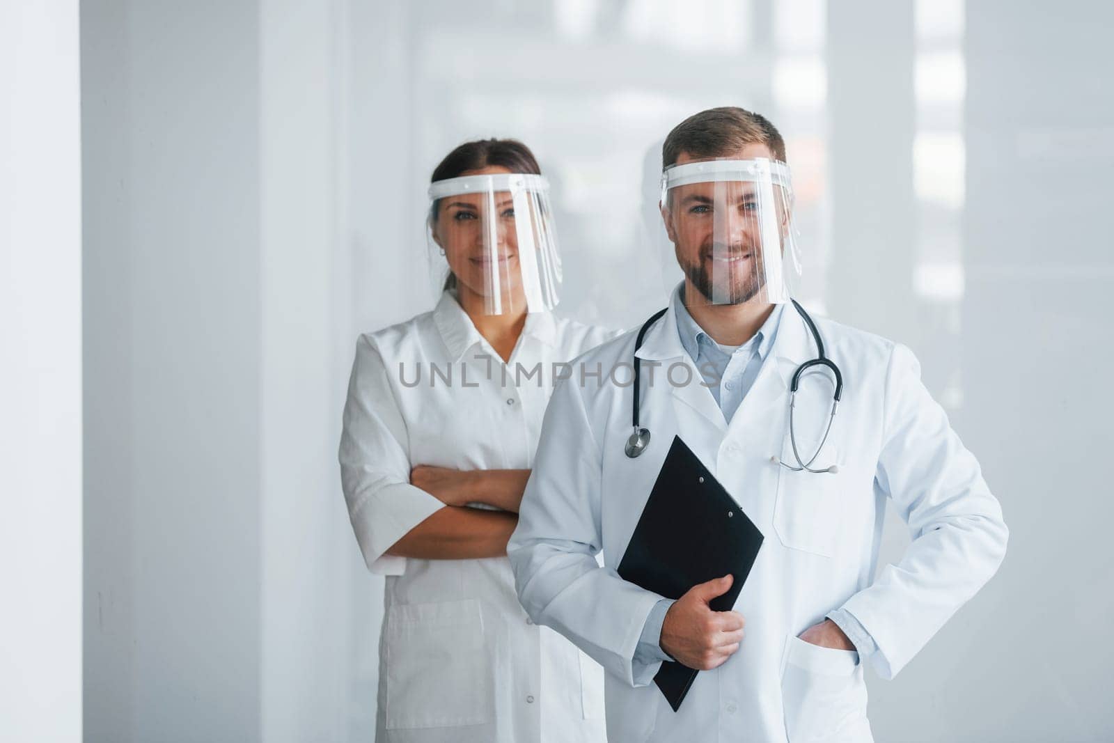 Front view. Two doctors in white coats is in the clinic working together.