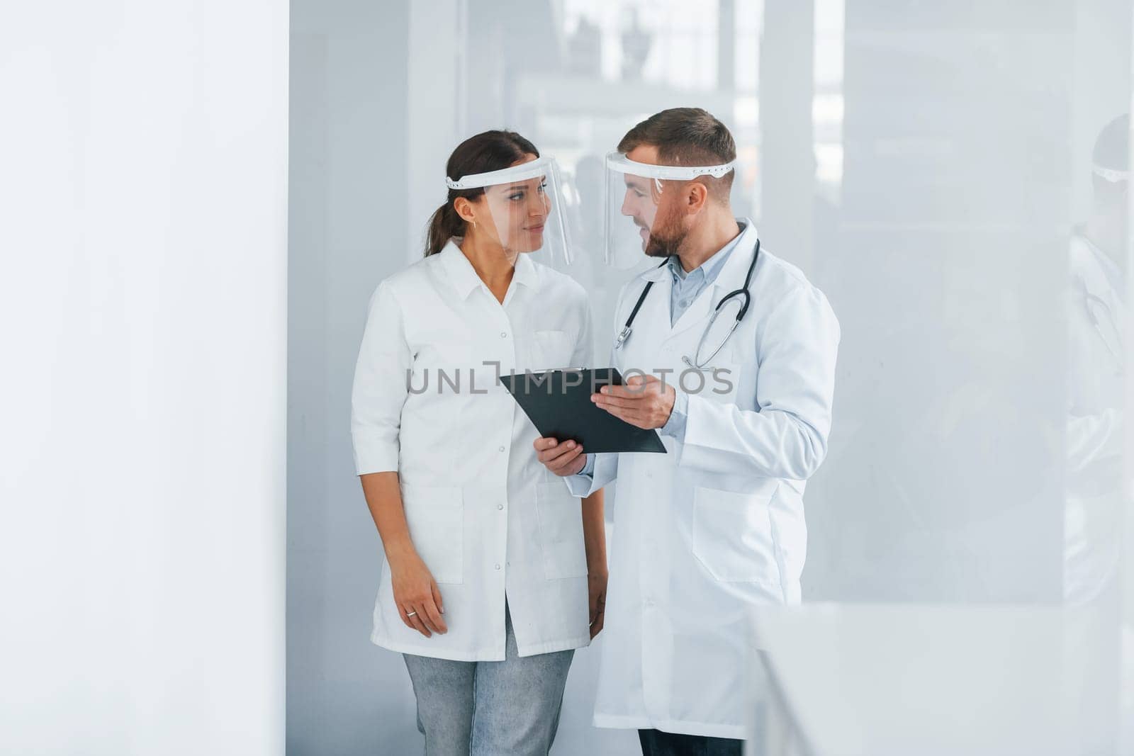 Front view. Two doctors in white coats is in the clinic working together.