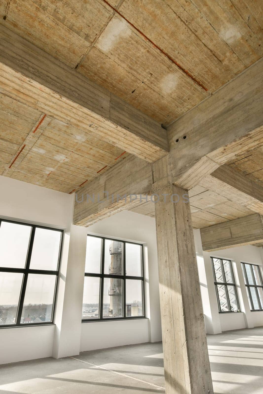 an empty room with wood beams on the ceiling and windows in the photo is taken from inside, looking out
