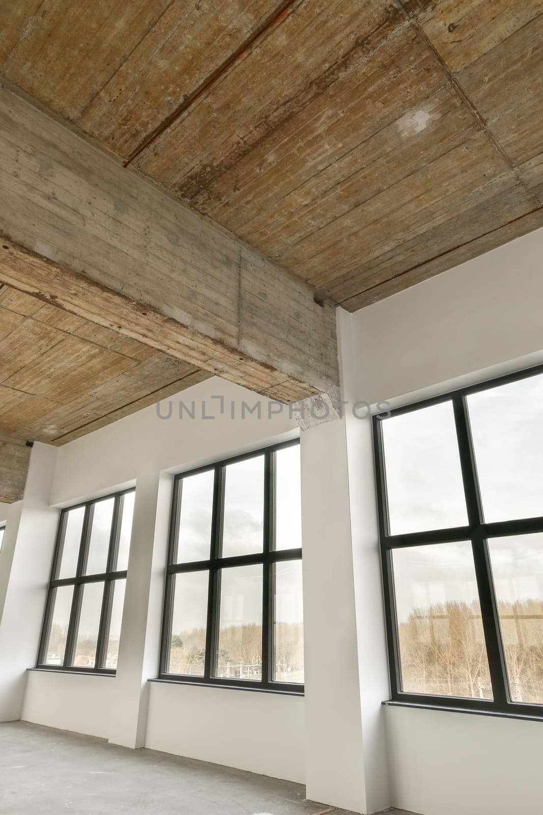 an empty room with large windows and wood planks on the ceiling that has been stripped down to make way for new flooring