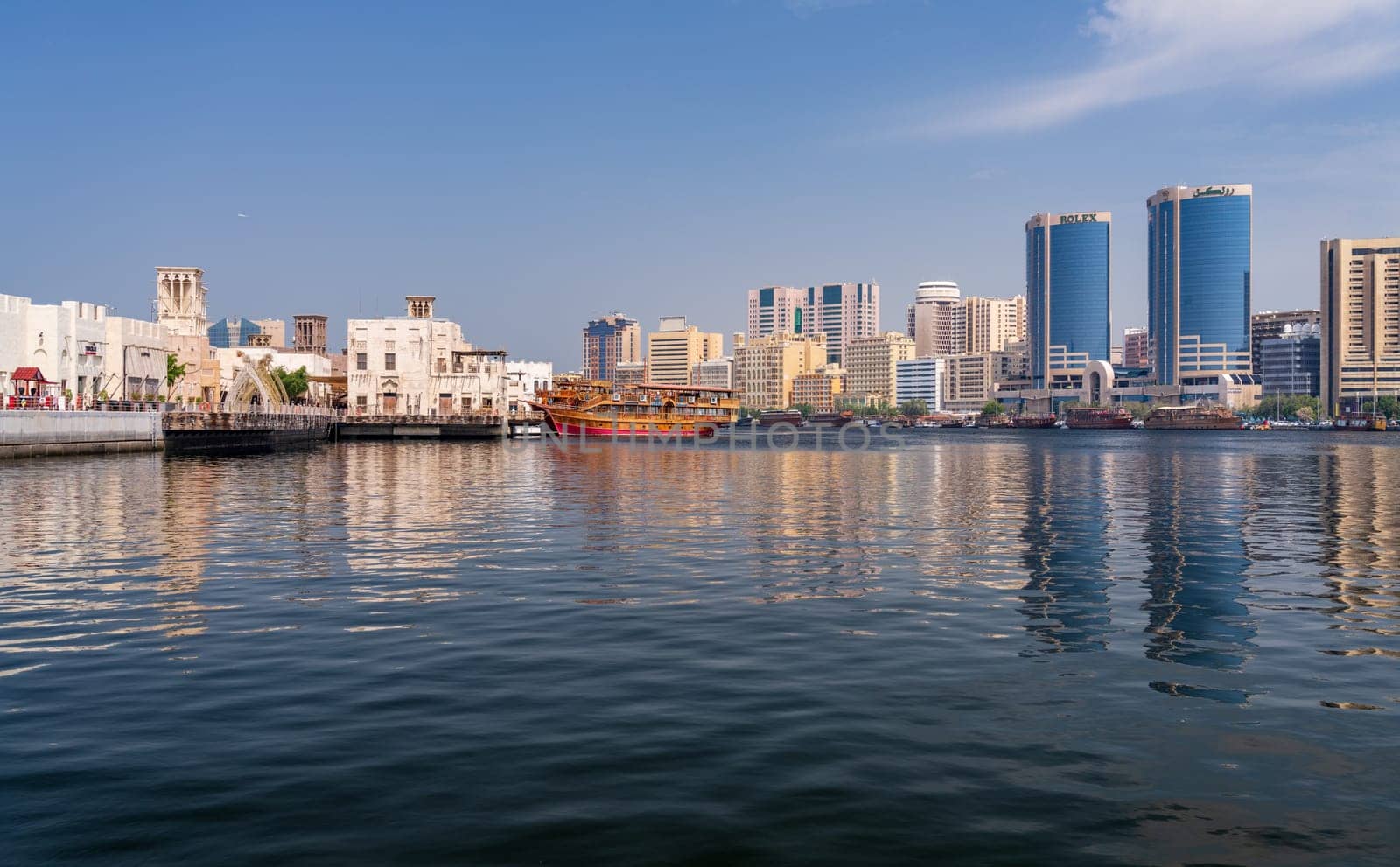 Dubai, UAE - 31 March 2023: View along the Creek towards Deira with large dhow tour boats docked by the Al Seef boardwalk