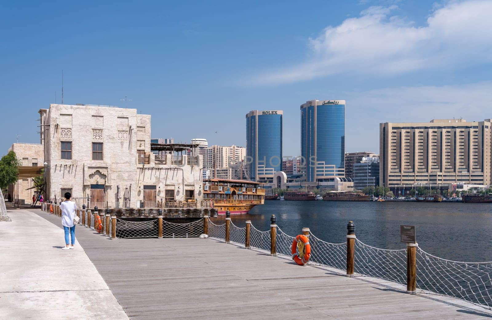 Dubai, UAE - 31 March 2023: View along the Creek towards Deira with large dhow tour boats docked by the Al Seef boardwalk