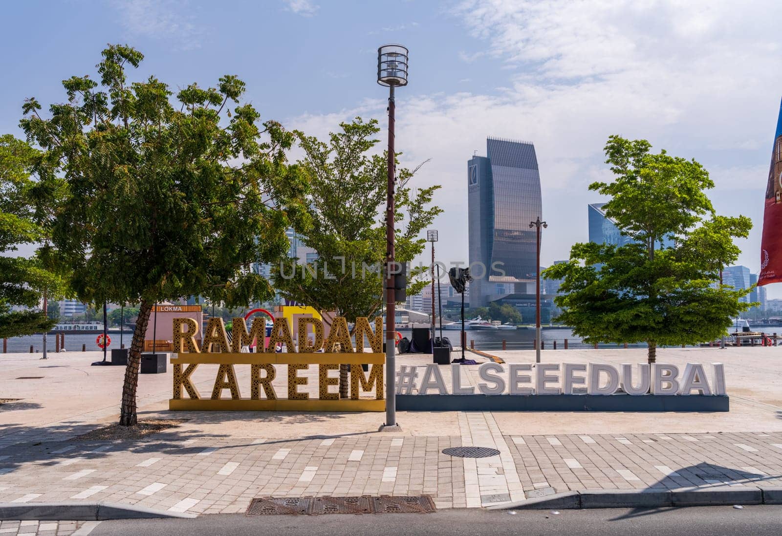 Dubai, UAE - 31 March 2023: View across the Creek towards Deira with hashtag sign for Ramadan on the Al Seef boardwalk