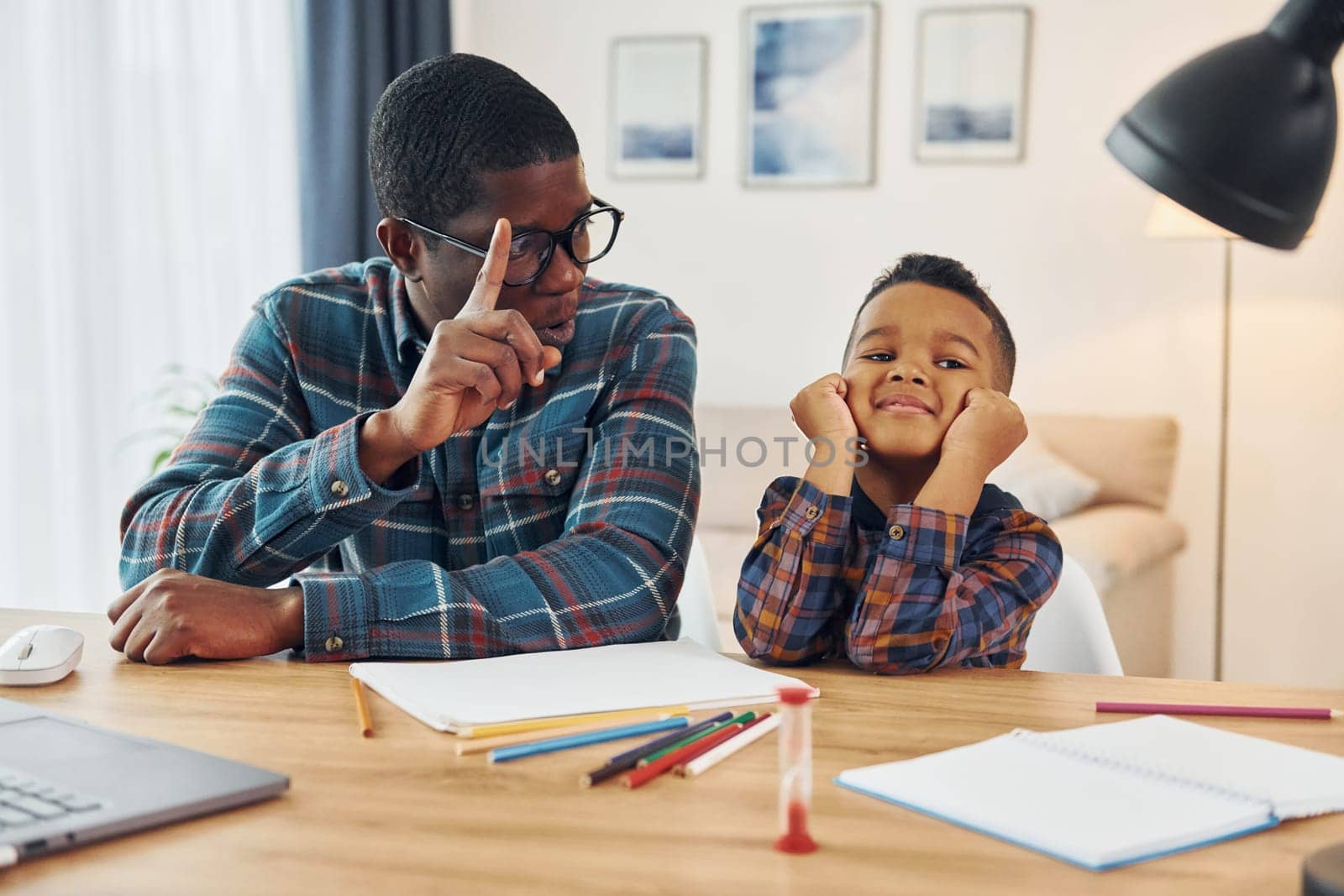 Cheerful family. African american father with his young son at home.
