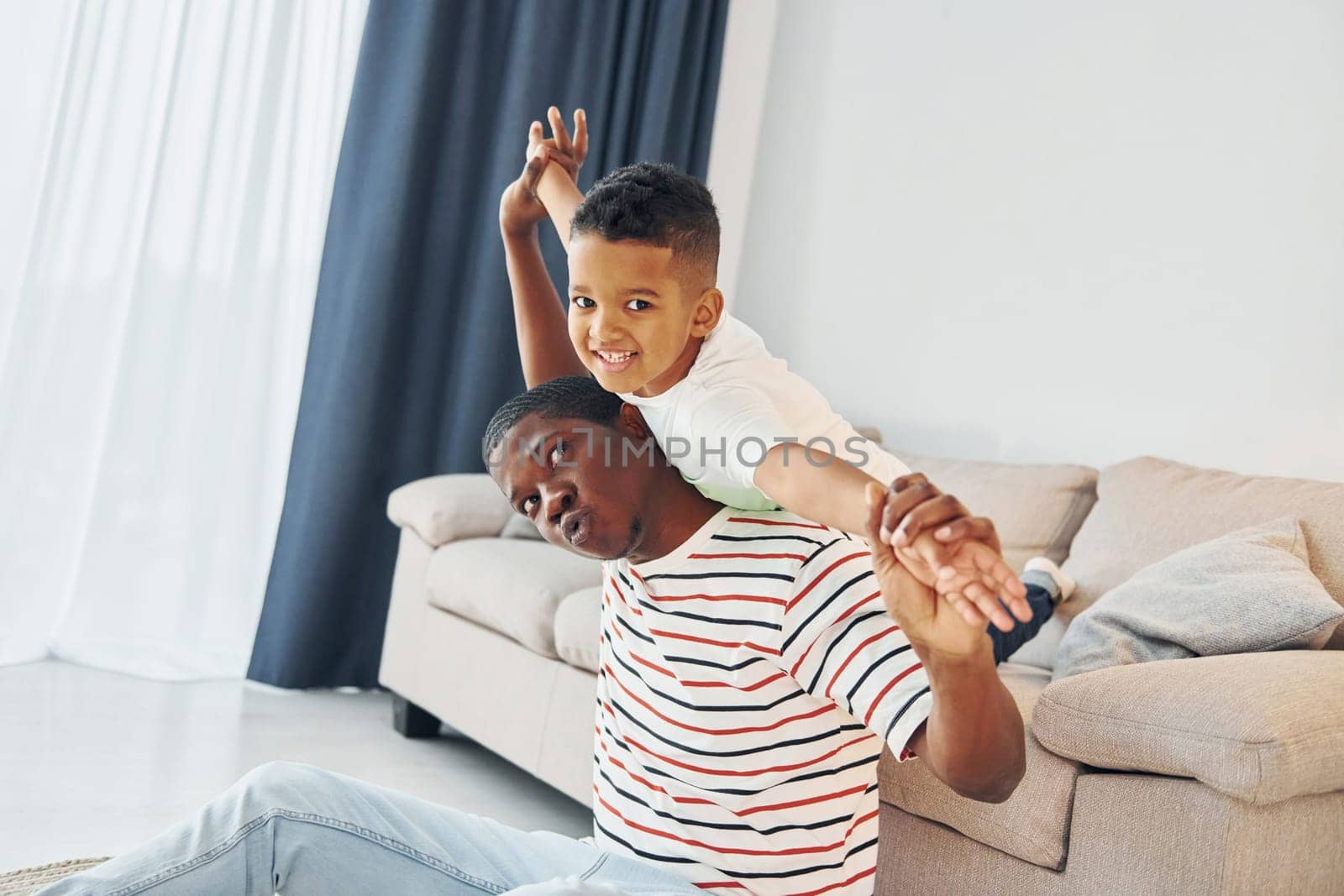 Active weekend time spending. African american father with his young son at home.