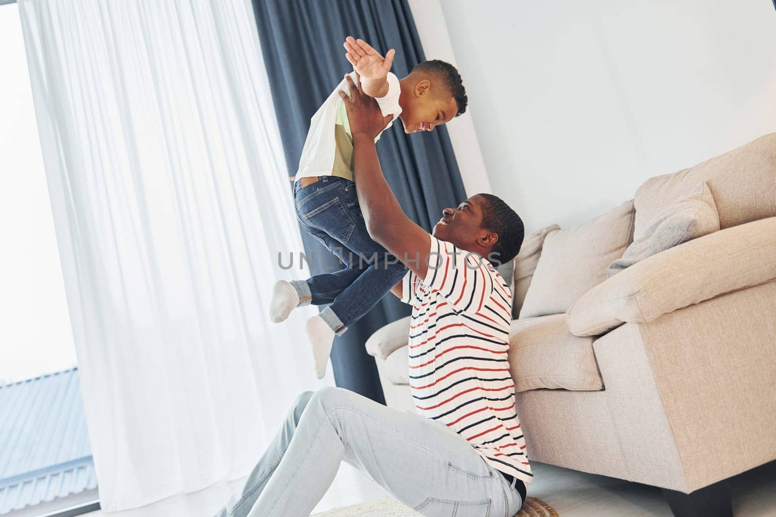 Active weekend time spending. African american father with his young son at home.