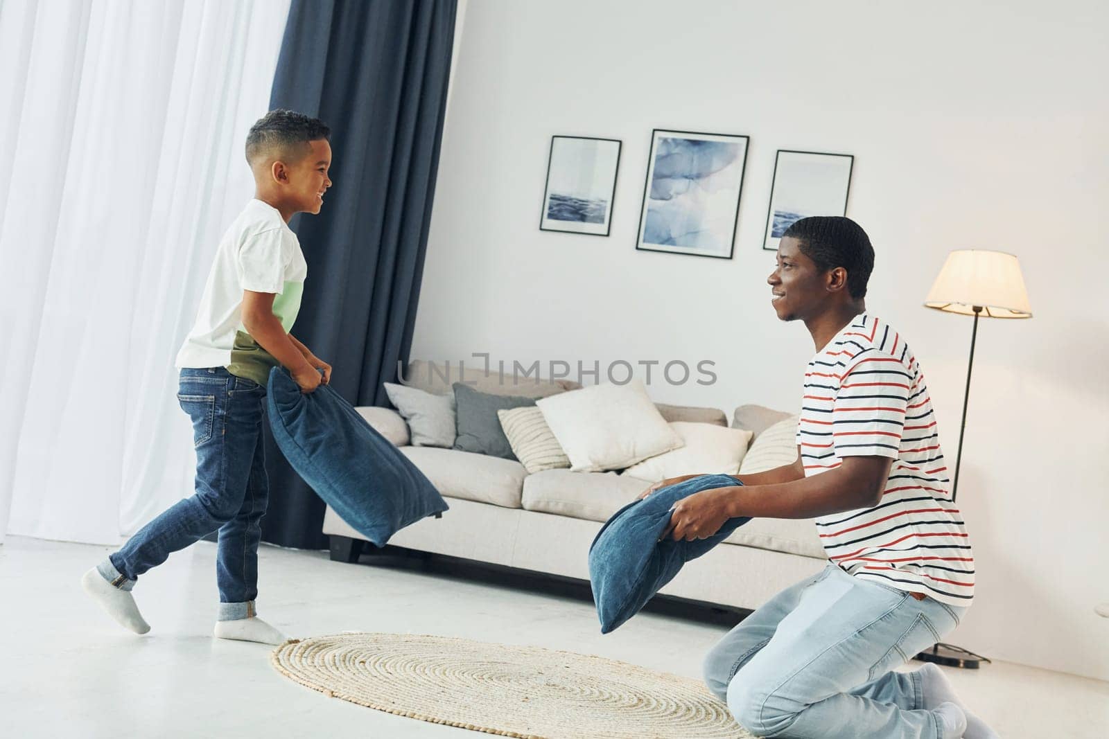Pillow fight. African american father with his young son at home.
