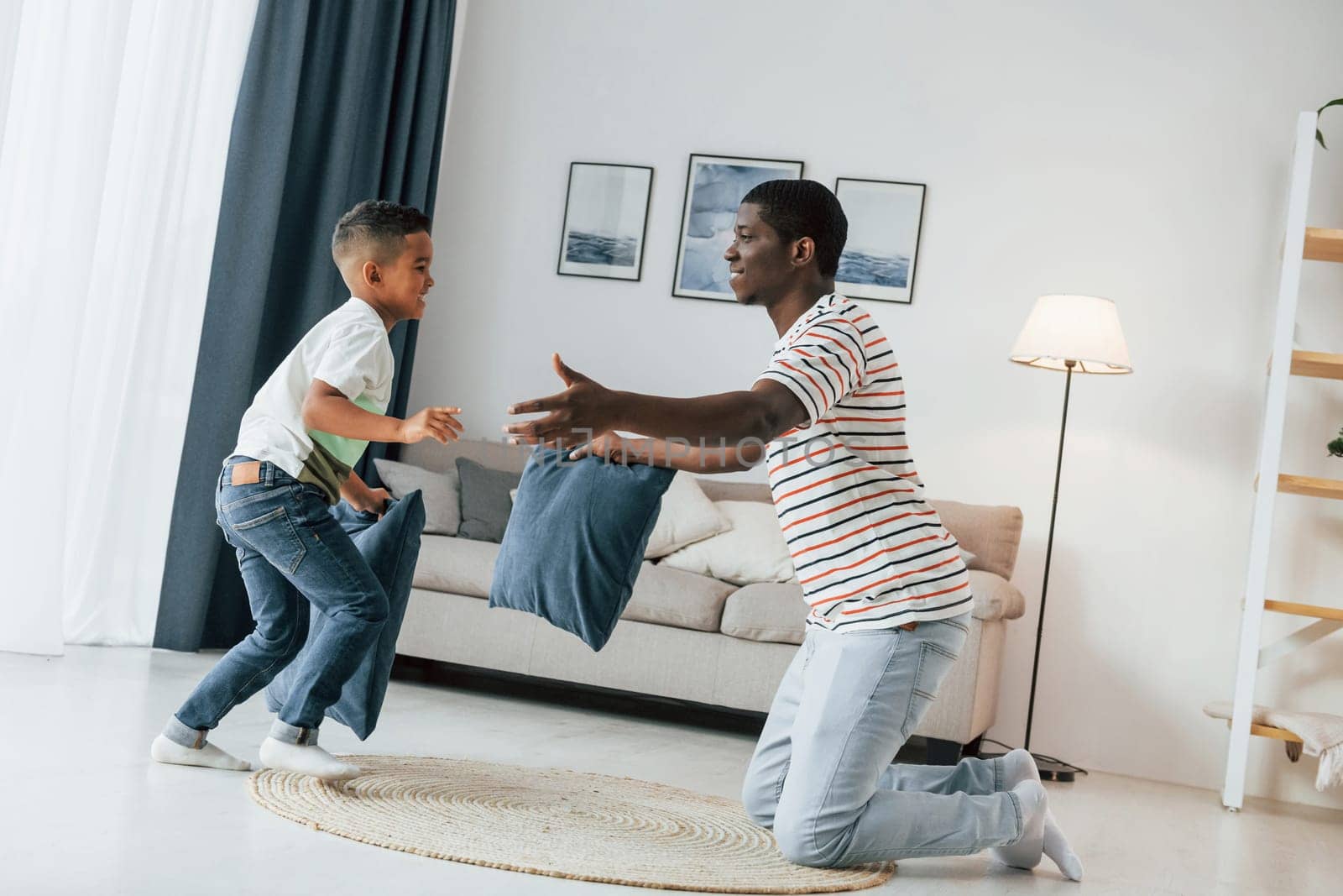 Pillow fight. African american father with his young son at home.