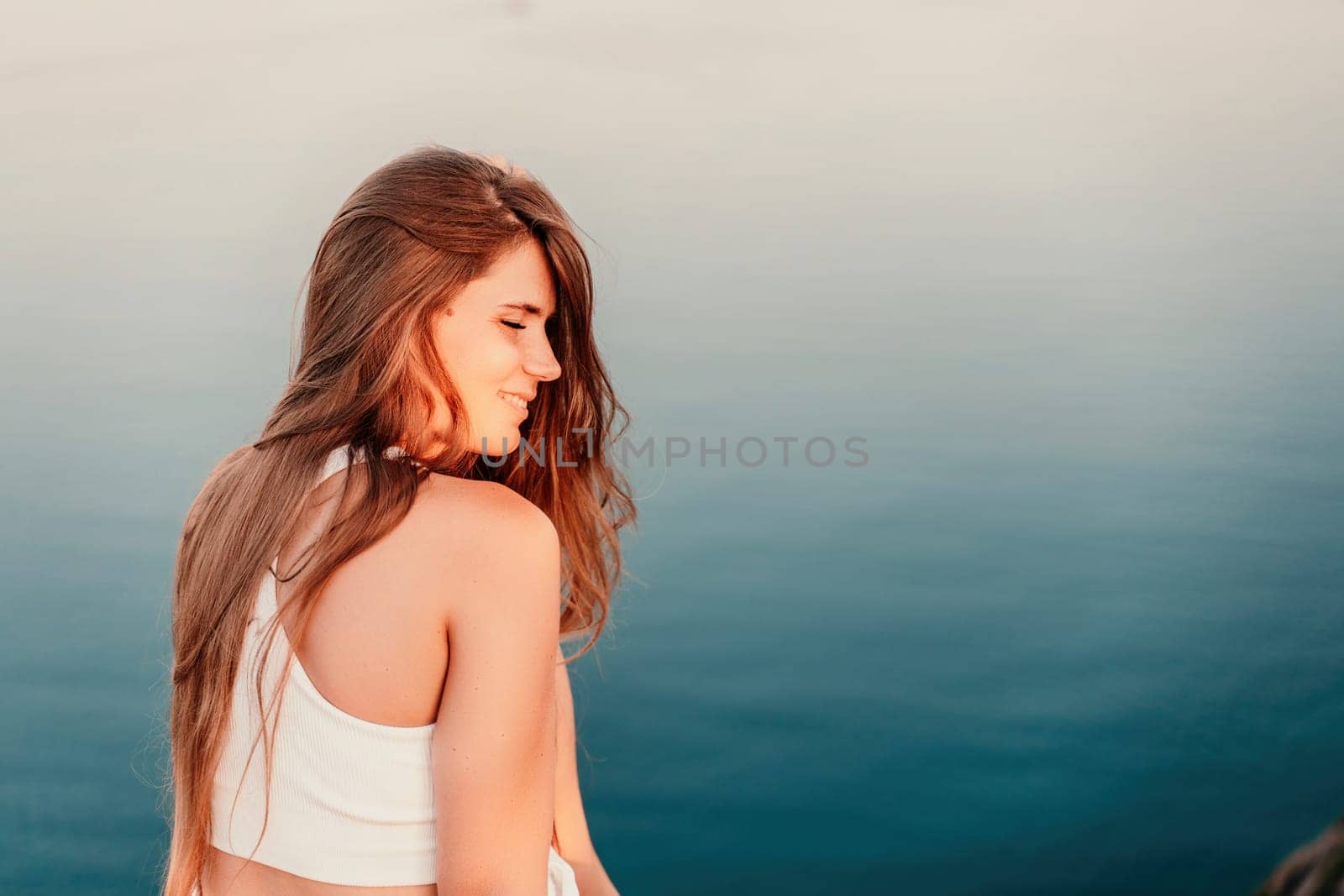 Portrait of a happy woman in a cap with long hair against the sea.