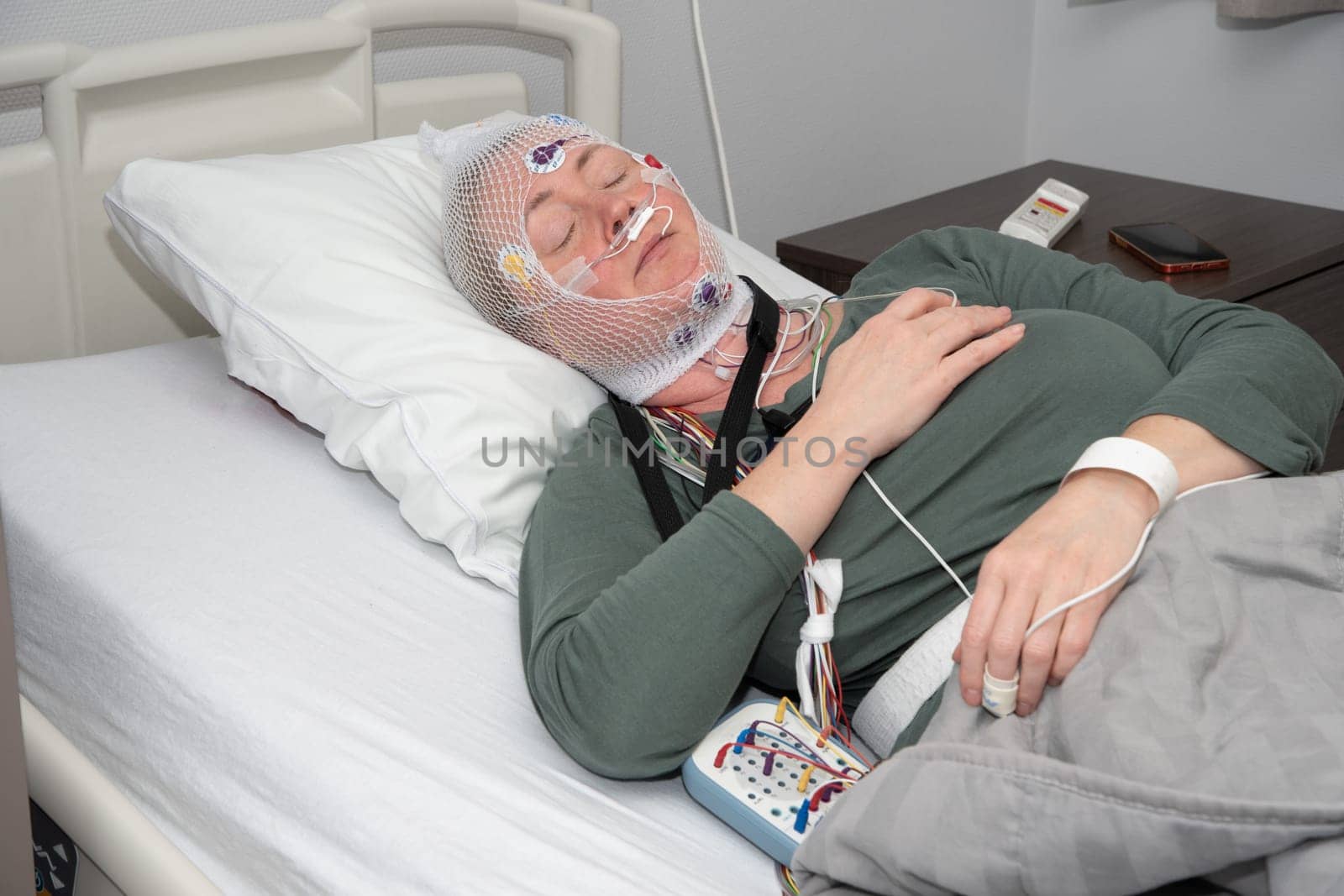 Middle aged woman measuring brain waves, examining polysomnography in sleep laboratory, High quality photo