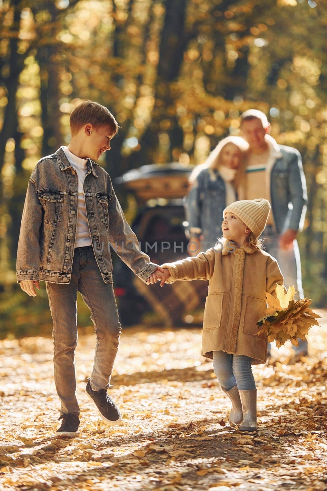 Sister with brother walking. Happy family is in the park at autumn time together.