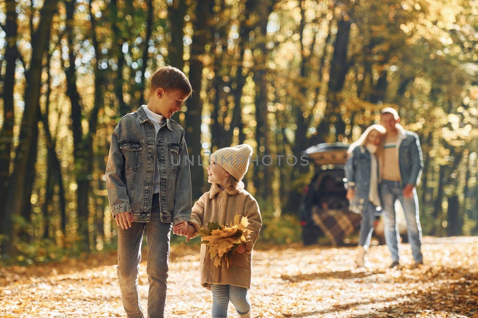 Sister with brother walking. Happy family is in the park at autumn time together.