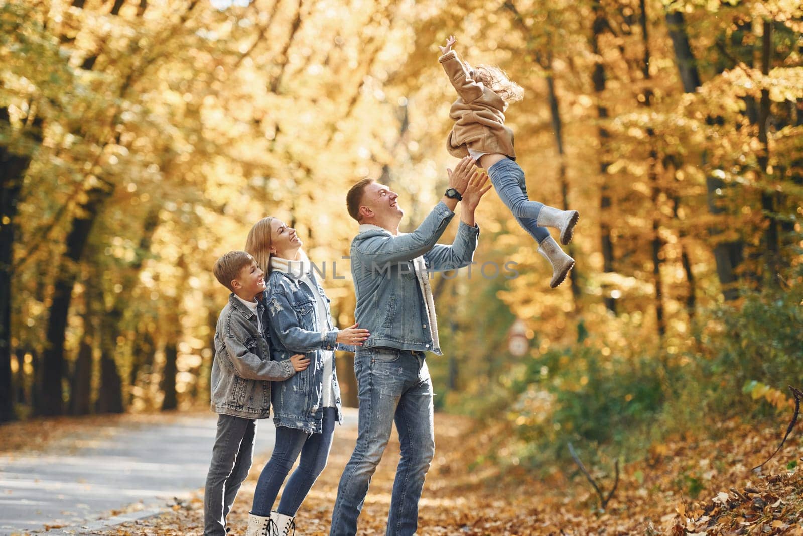 Four people. Happy family is in the park at autumn time together.