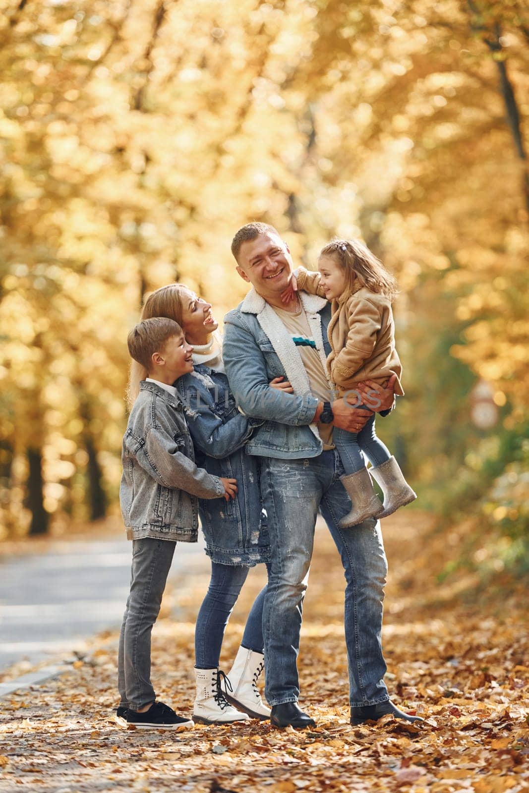 Near the road. Happy family is in the park at autumn time together.