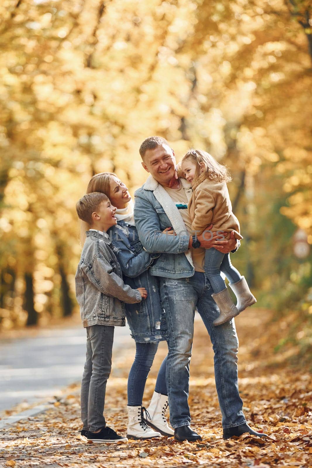 Near the road. Happy family is in the park at autumn time together.