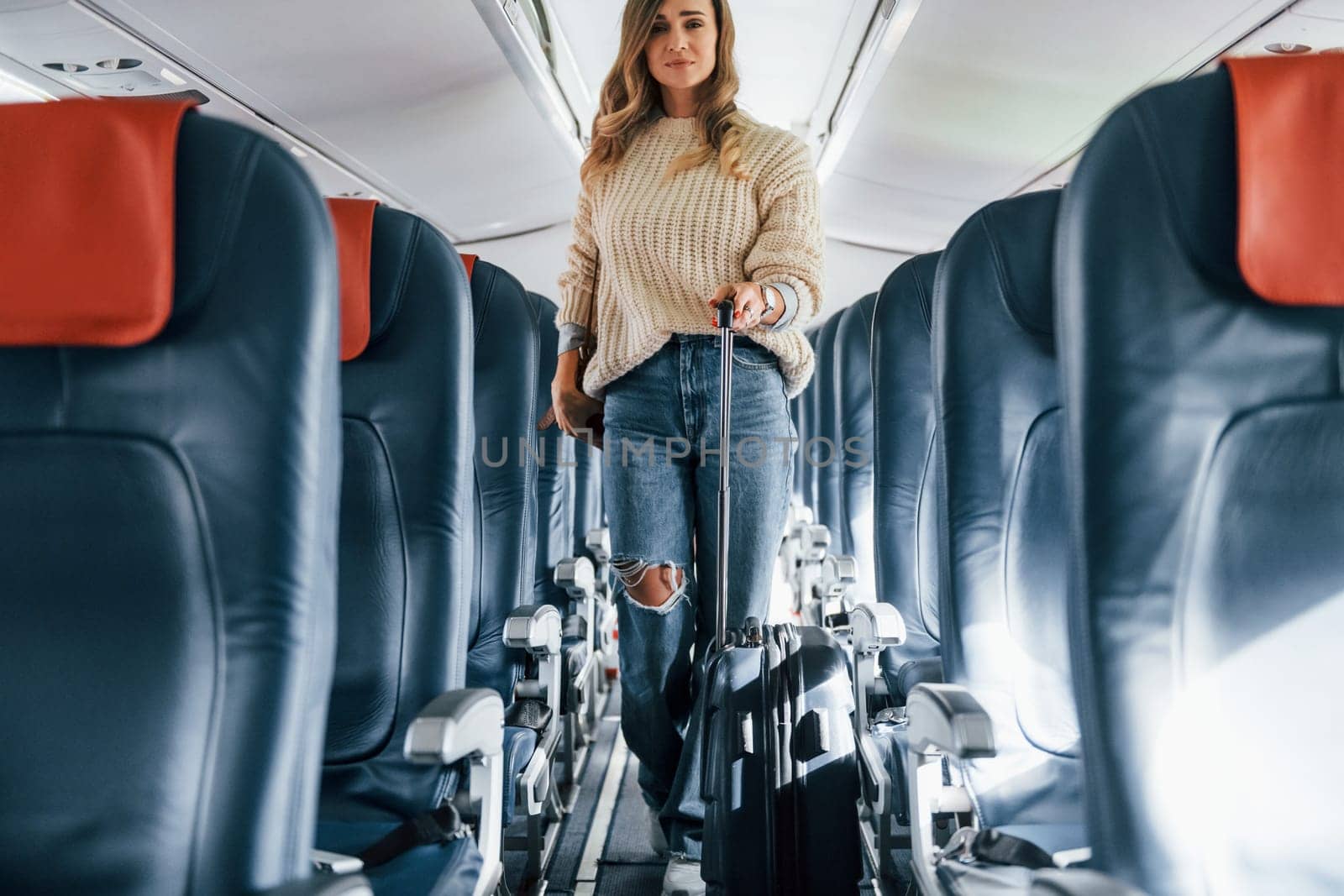 Front view. Young female passanger in casual clothes is in the plane.
