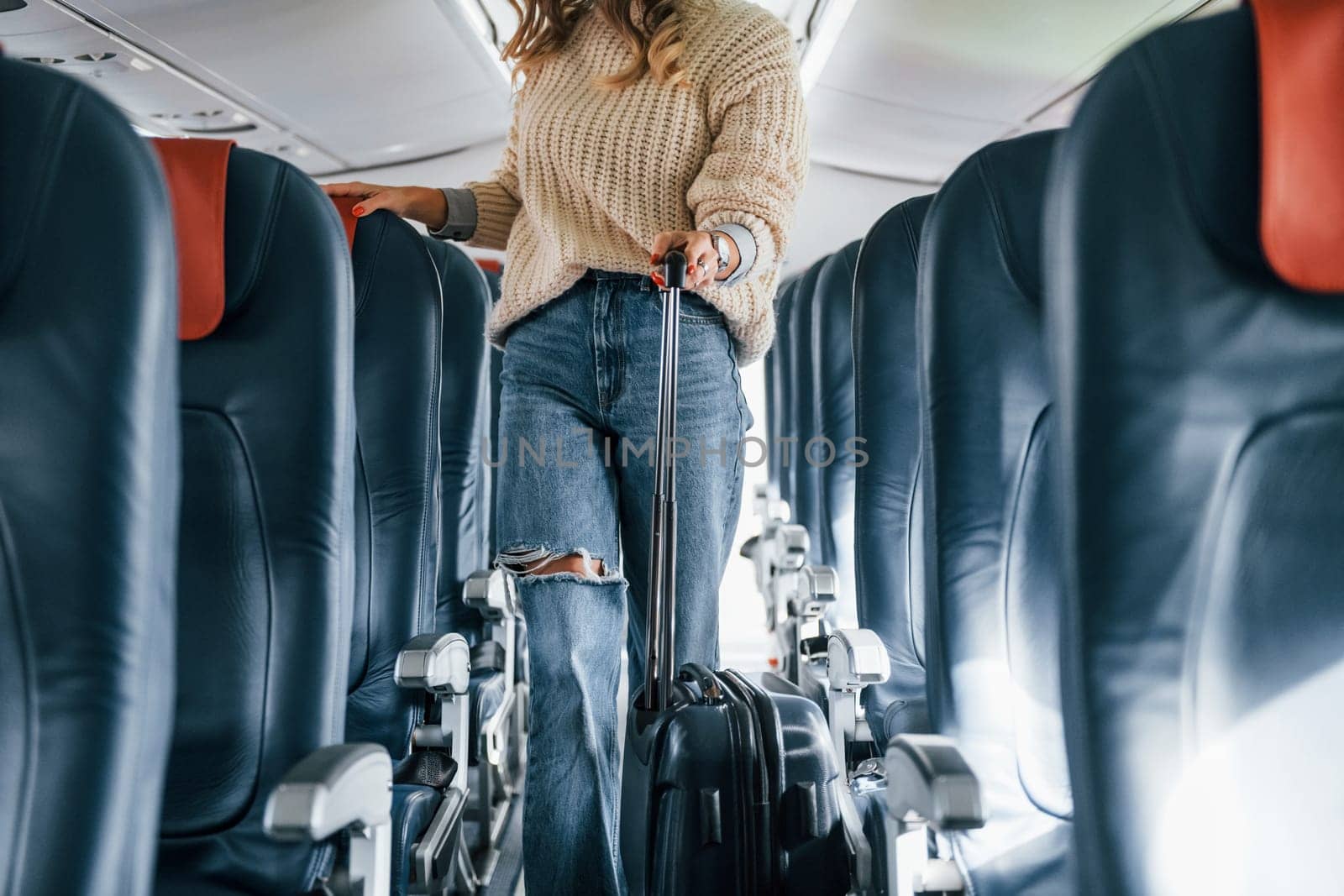 Front view. Young female passanger in casual clothes is in the plane.